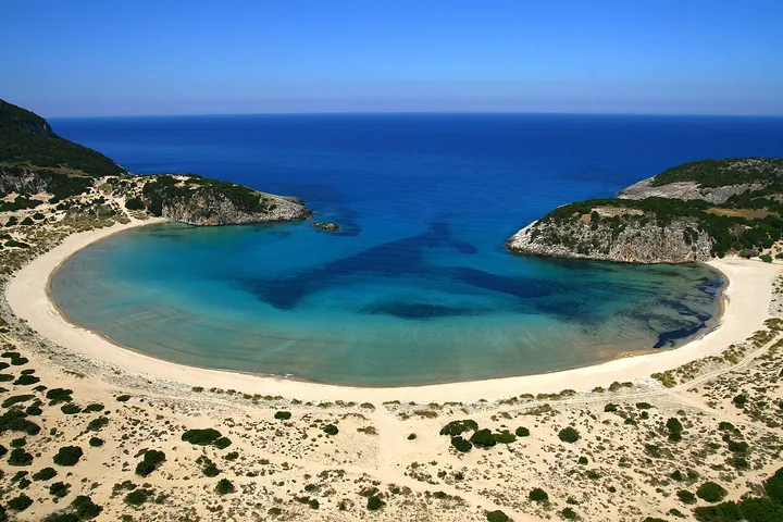Curved sandy shoreline of Voidokilia Beach in Messinia, Greece.
